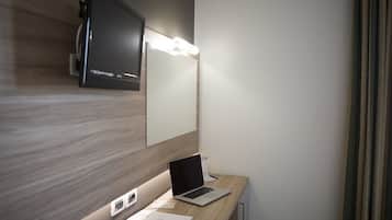 Una habitación de hotel moderna con un escritorio de madera, una computadora portátil y un televisor montado en la pared.