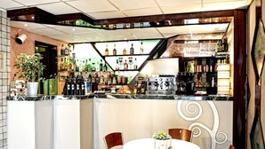 A bar area with a counter, seating, and a variety of bottles and glasses. - Hotel Prestige (Montesilvano)