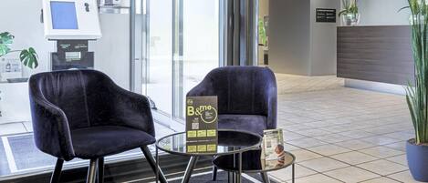A reception area with two dark blue chairs, a glass table, and a reception desk.