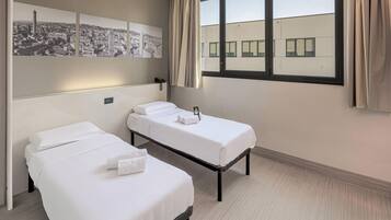 Ein Hotelzimmer mit zwei Einzelbetten, einem Stadtbild als Wandkunst, einem Nachttischtelefon und einem Vorhangfenster.