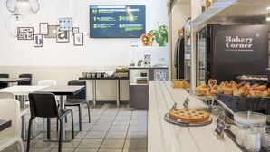 A bakery counter with pastries and a coffee machine. There are tables and chairs in the background. - B&B Hotel Bologna (Castel Maggiore)