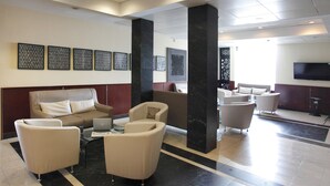 Una hall moderna con un divano, poltrone, un tavolino da caffè e un televisore a schermo piatto.
