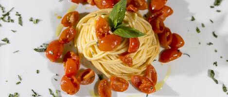 A plate of spaghetti with cherry tomatoes and basil.
