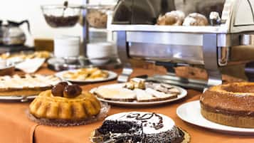 Una mesa de bufé con diversos postres y una máquina de café.