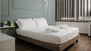 Una moderna camera d'albergo con un letto, comodini, un tavolino e una finestra con tende.