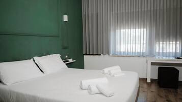 Una habitación de hotel con una cama grande, un escritorio y una ventana con cortinas.
