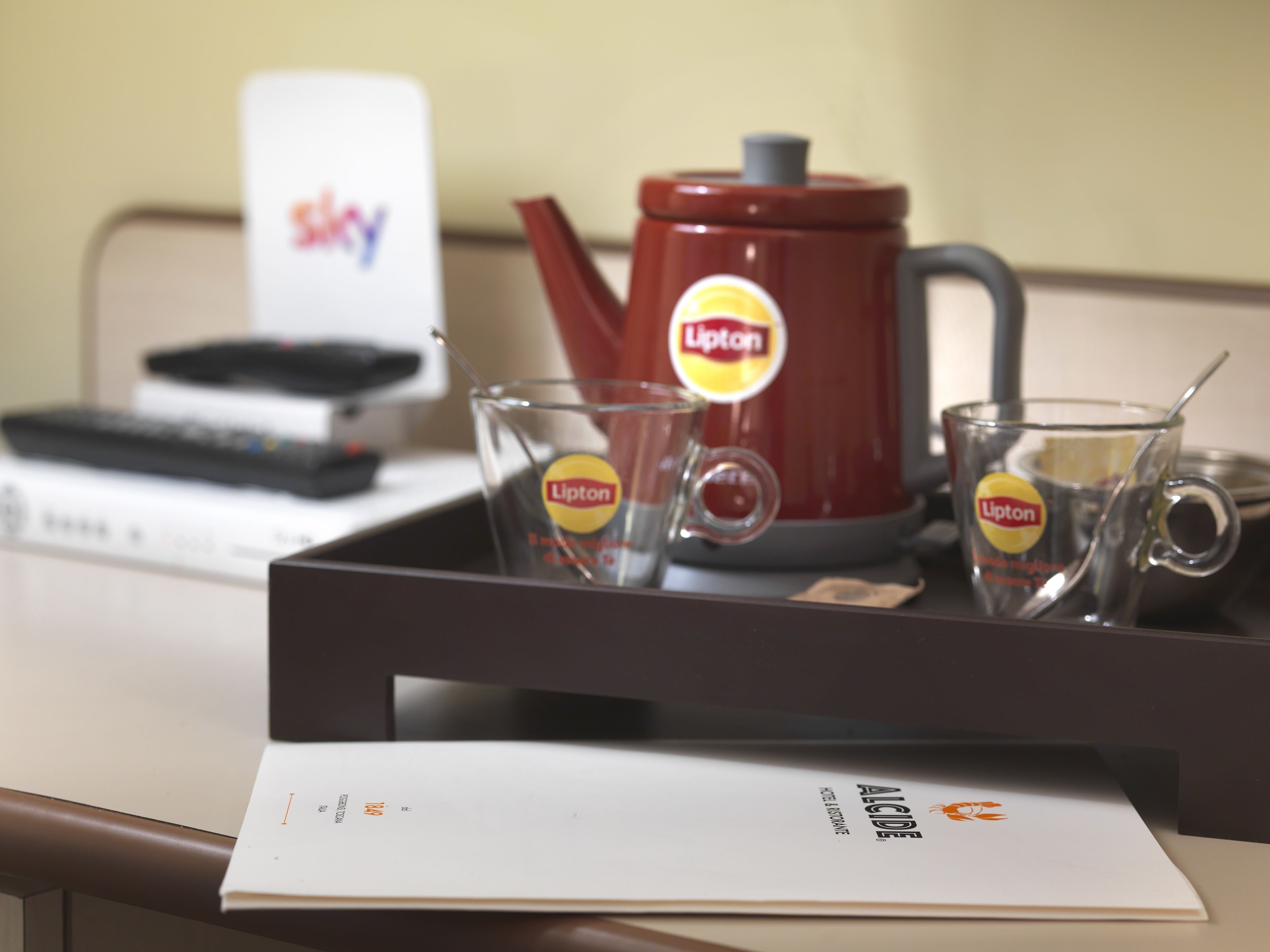 A tray with a Lipton tea kettle, two Lipton tea glasses, and a tray of documents.