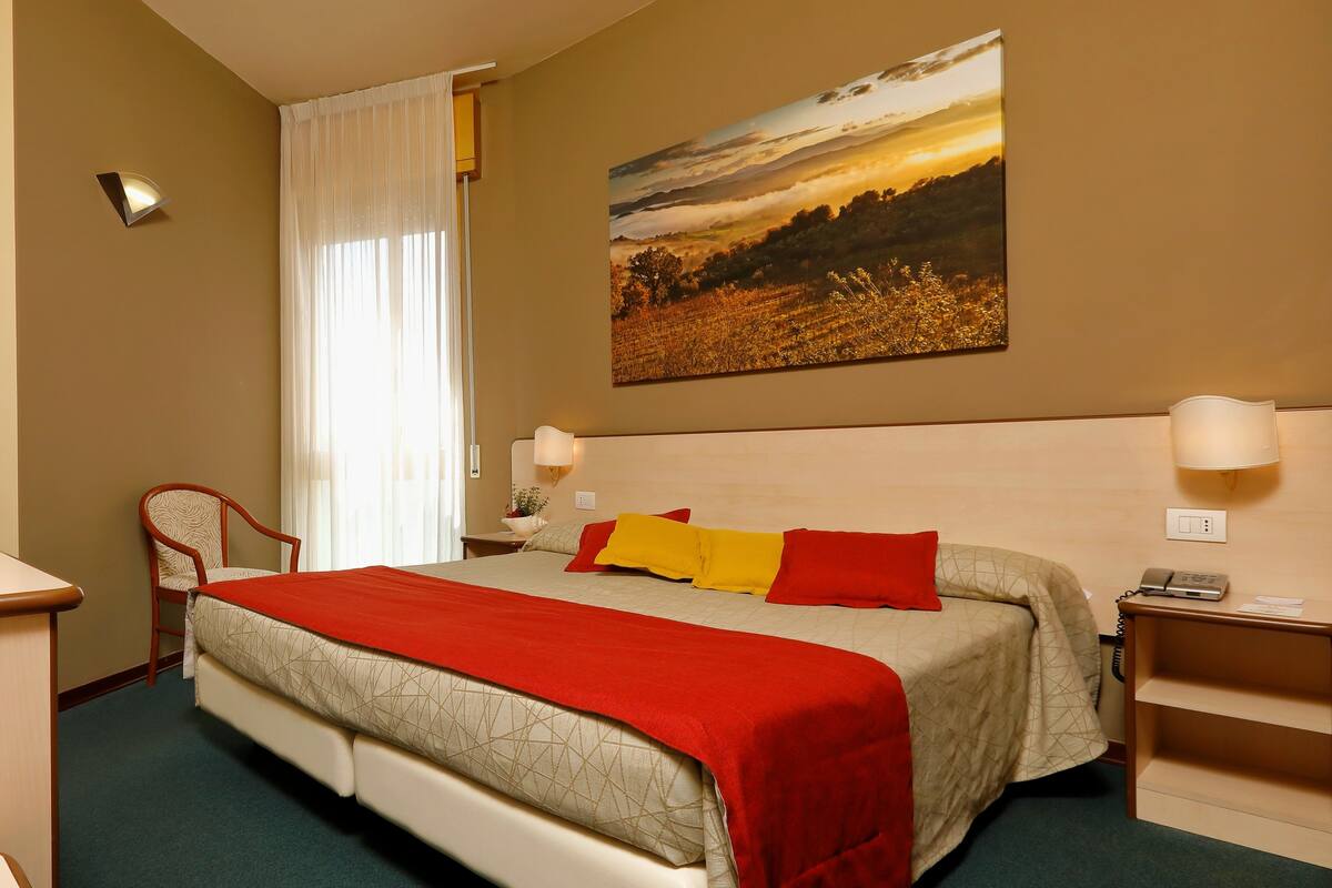 Une chambre d’hôtel avec un grand lit, une chaise, une table de chevet et un tableau au mur.