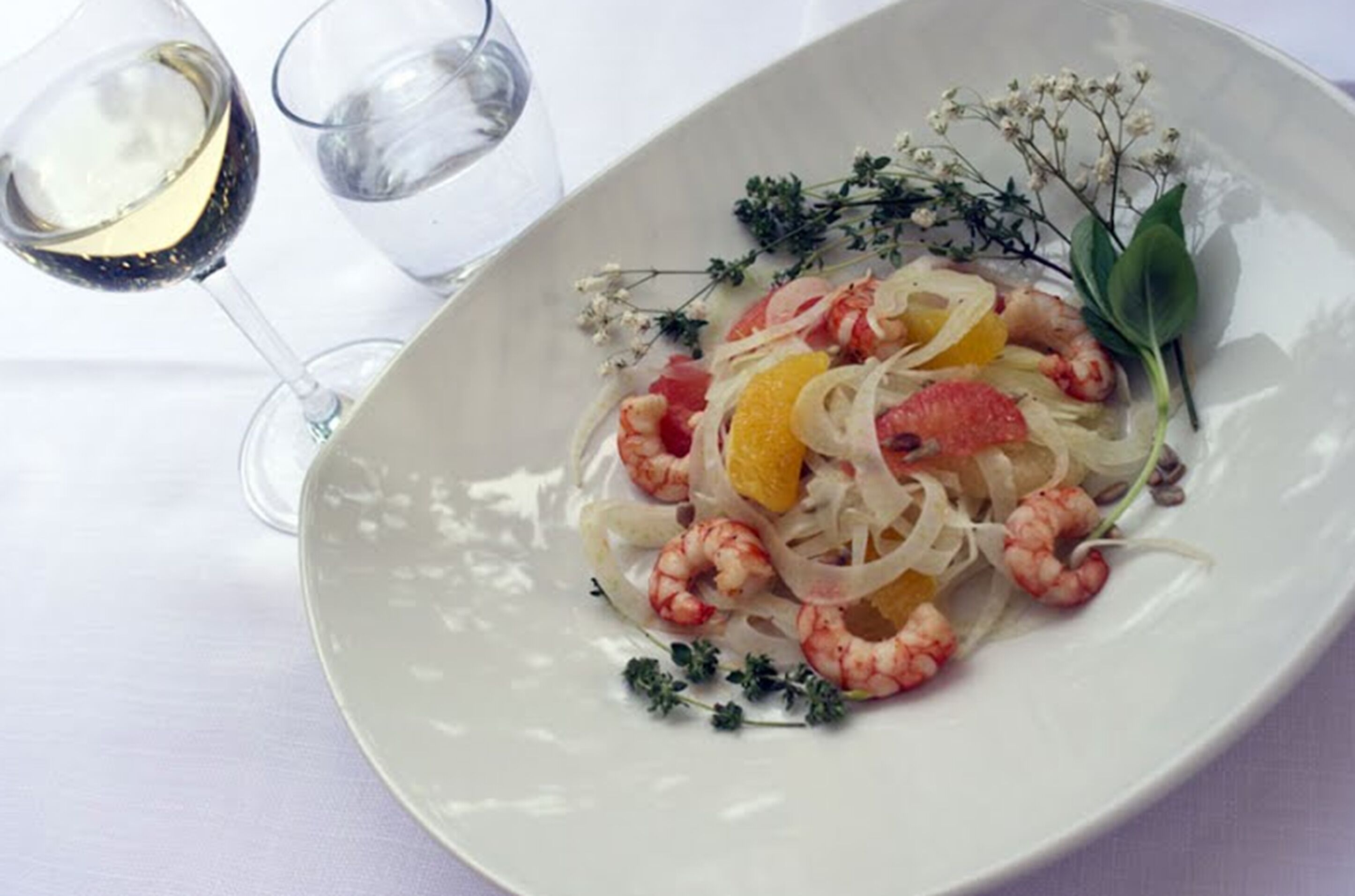 A plate of seafood pasta with a glass of white wine.