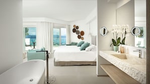 Un dormitorio moderno con una cama grande, una bañera y un baño con lavabo y espejos.