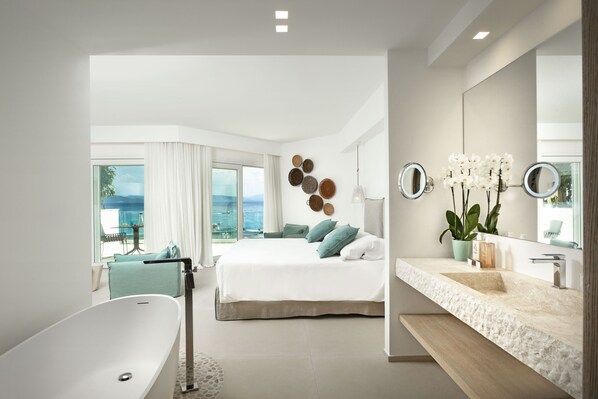 Un dormitorio moderno con una cama grande, una bañera y un baño con lavabo y espejos.