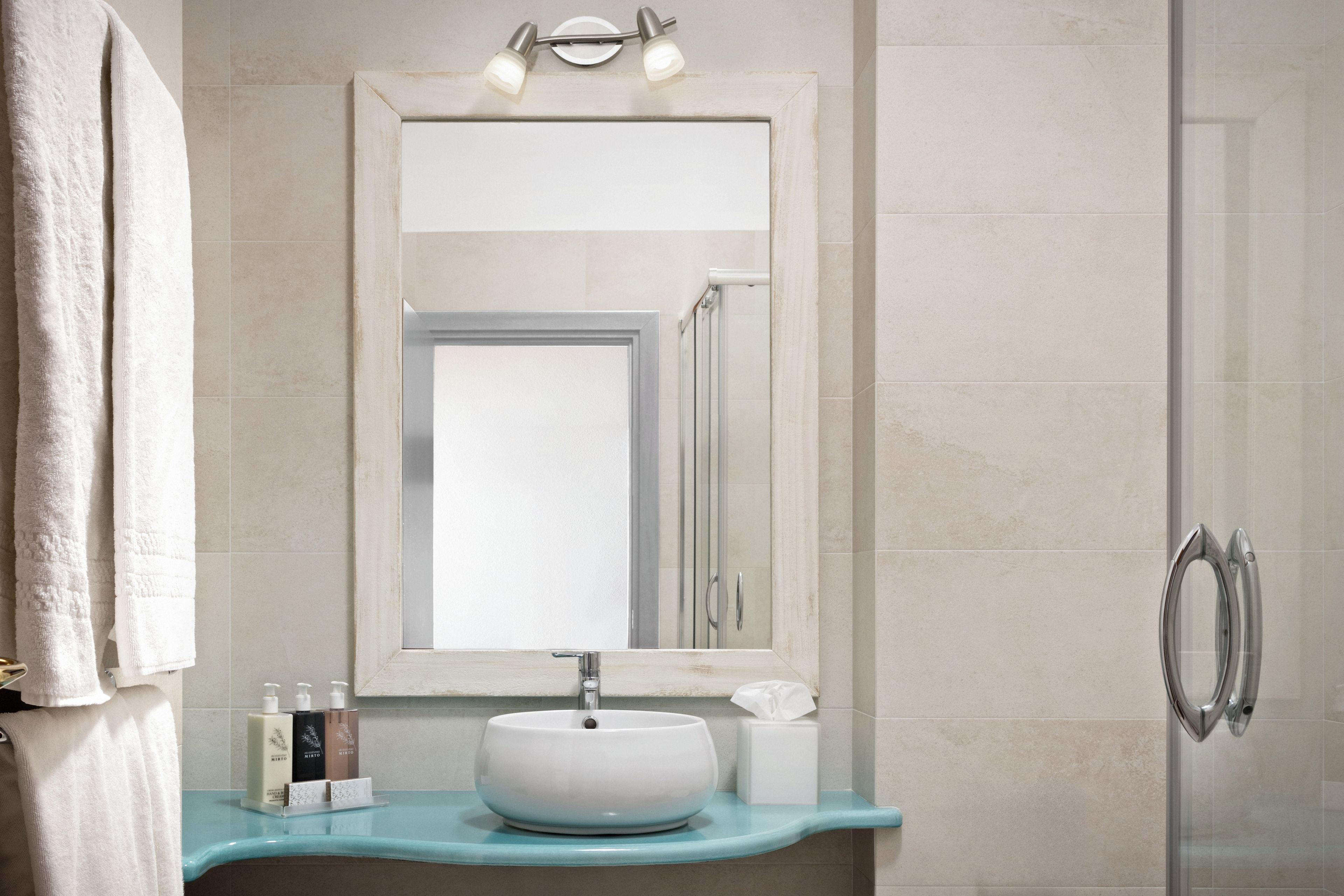 A bathroom with a white sink, a mirror above it, and a towel rack to the left.