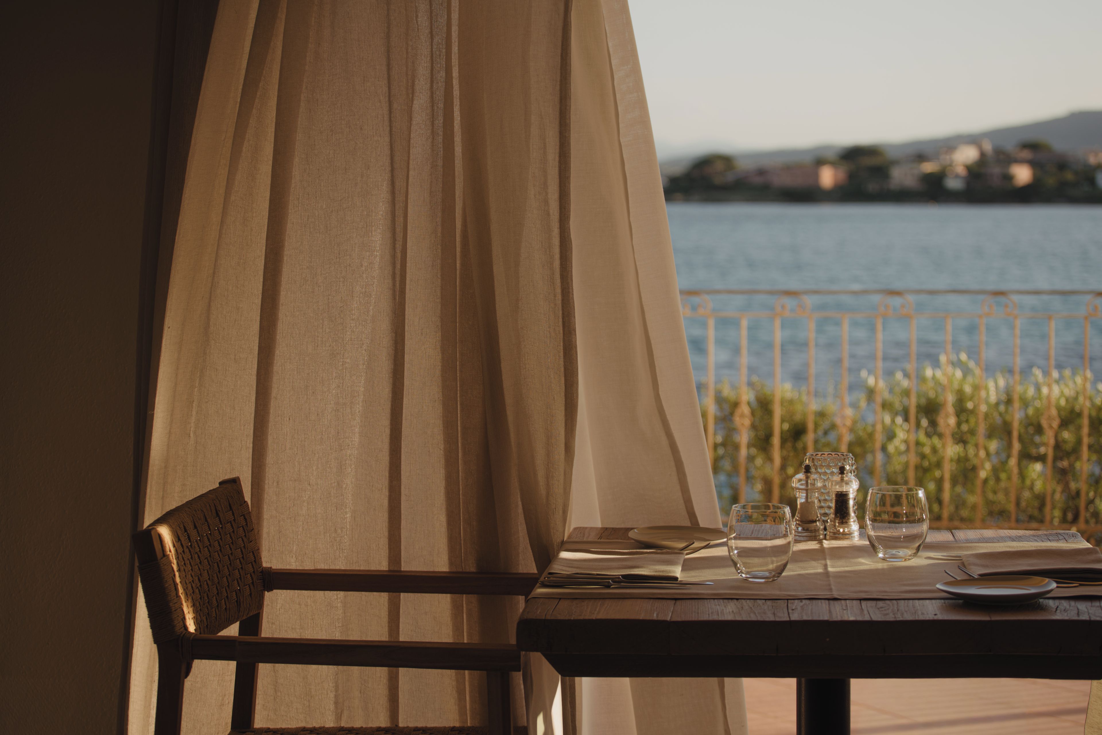 A table set for two with a view of a body of water and a distant landscape.