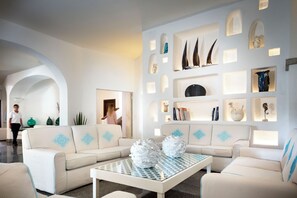 Een moderne woonkamer met een hoekbank, een glazen salontafel en decoratieve objecten op planken.
