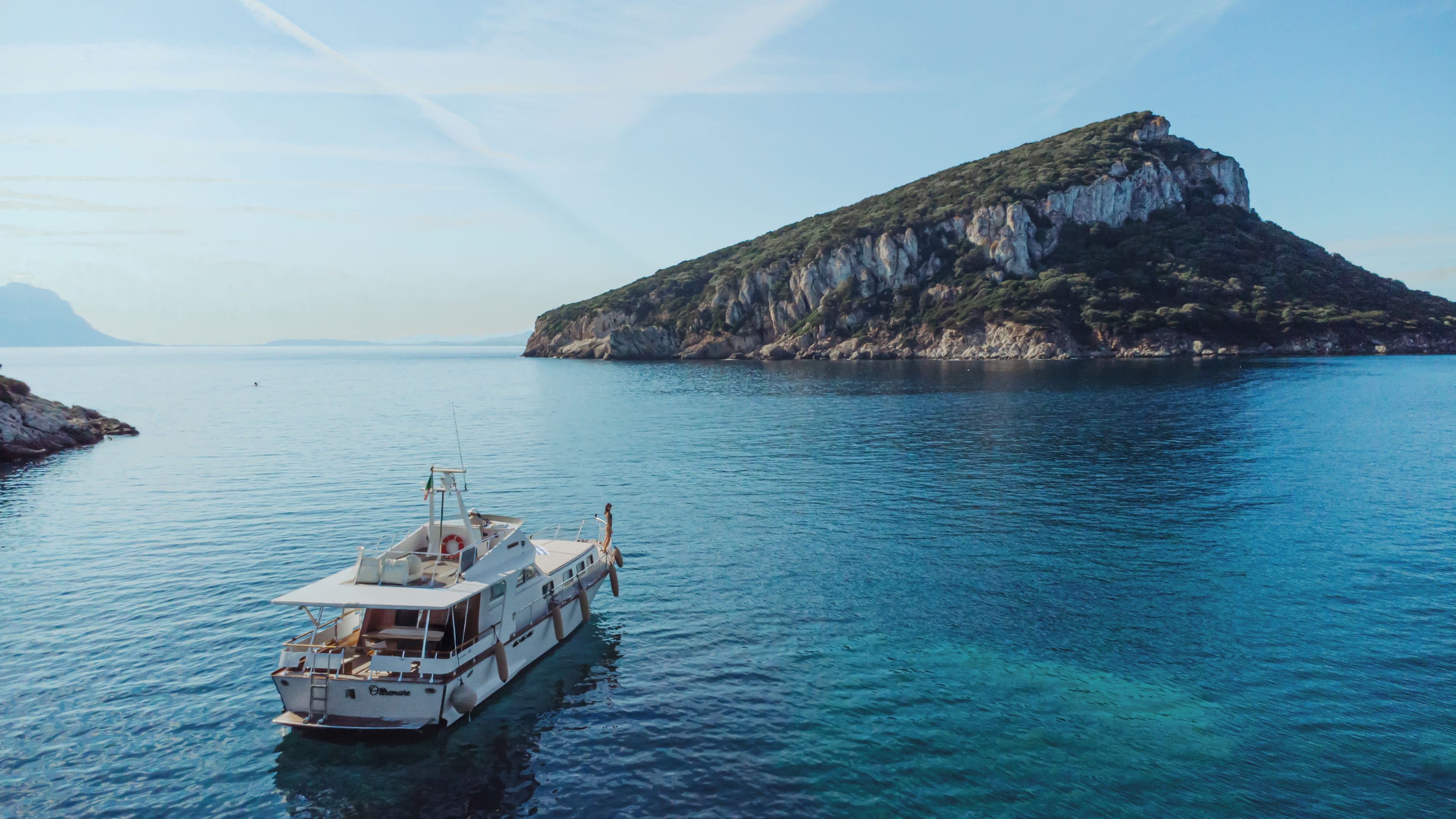 A boat on clear blue water with a rocky island in the background.
