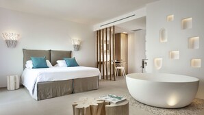 Een moderne slaapkamer met een groot bed, een vrijstaand bad en een houten salontafel.