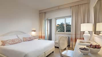 Ein Hotelzimmer mit einem Bett, einem Schreibtisch mit Lampe, einem Sessel und einer Obstschale.