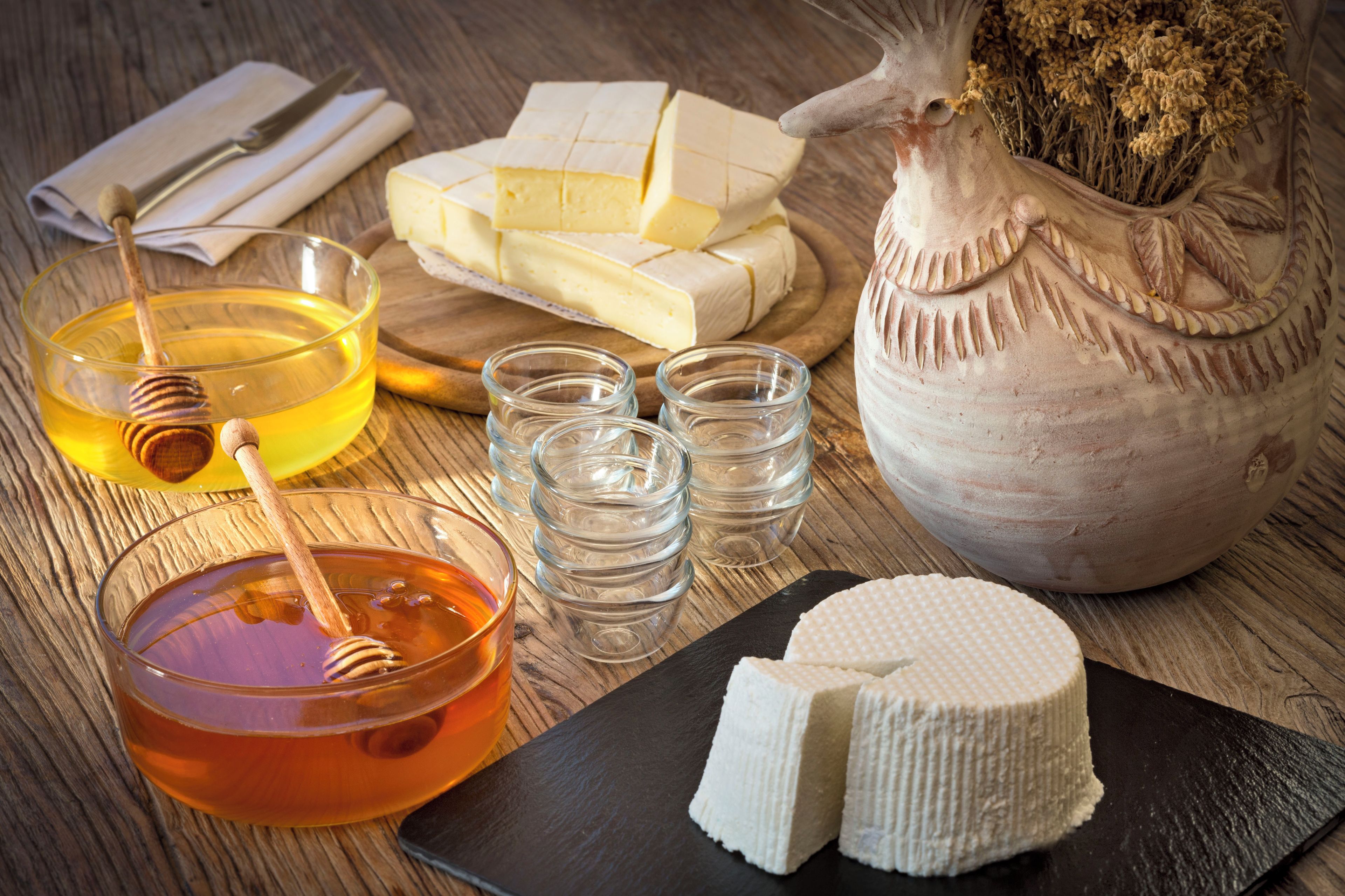 Una mesa de madera con diversos alimentos, incluyendo queso, miel y un cucharón de miel.