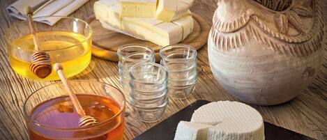 A wooden table with various food items including cheese, honey, and honey dipper.