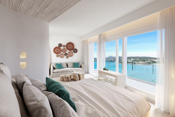 Een moderne slaapkamer met een groot bed, een zithoek met een bank en fauteuils, een klein tafeltje, en uitzicht op zee.