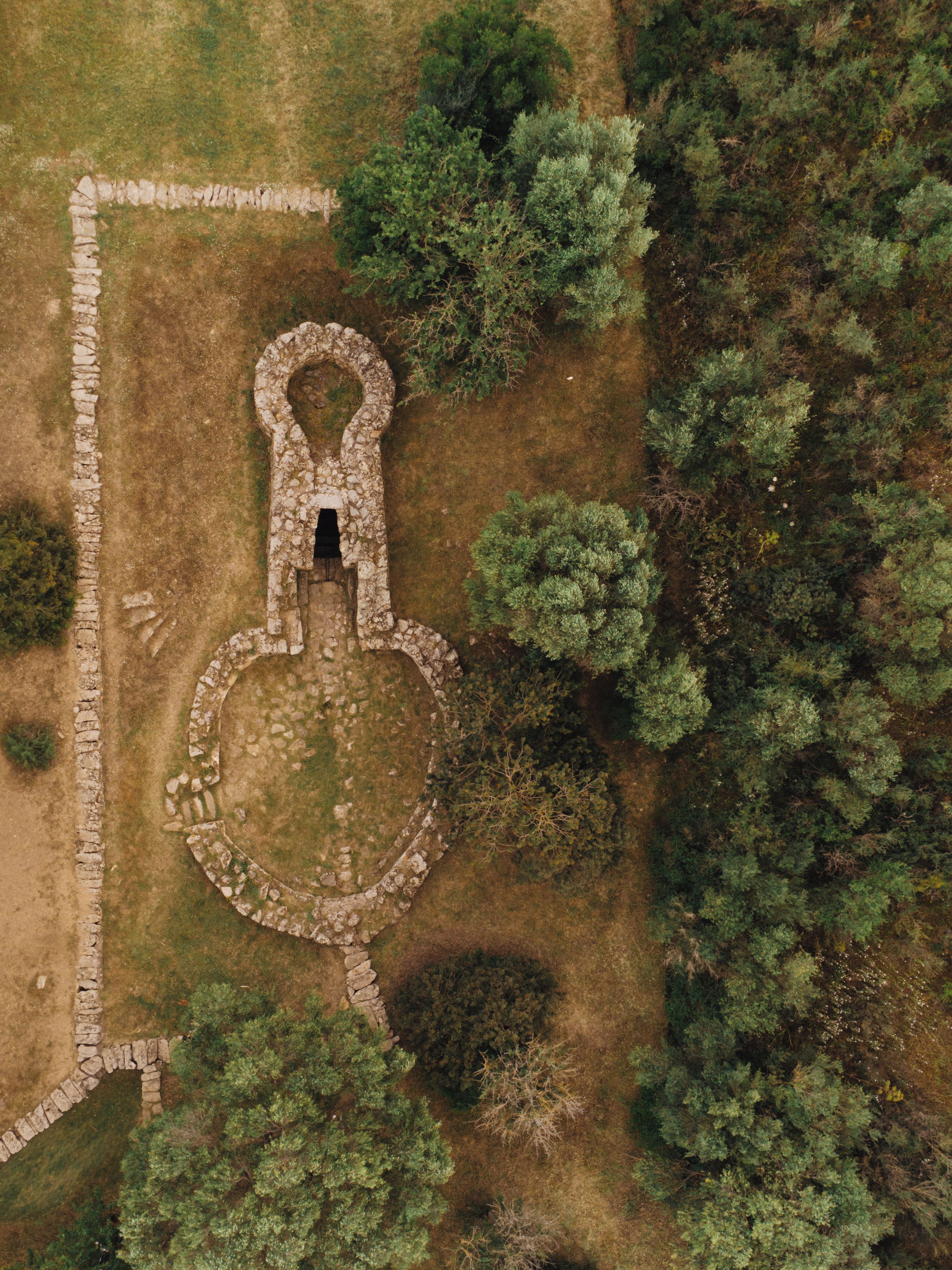 Une vue aérienne d’une structure circulaire en pierre, entourée d’une forêt dense.