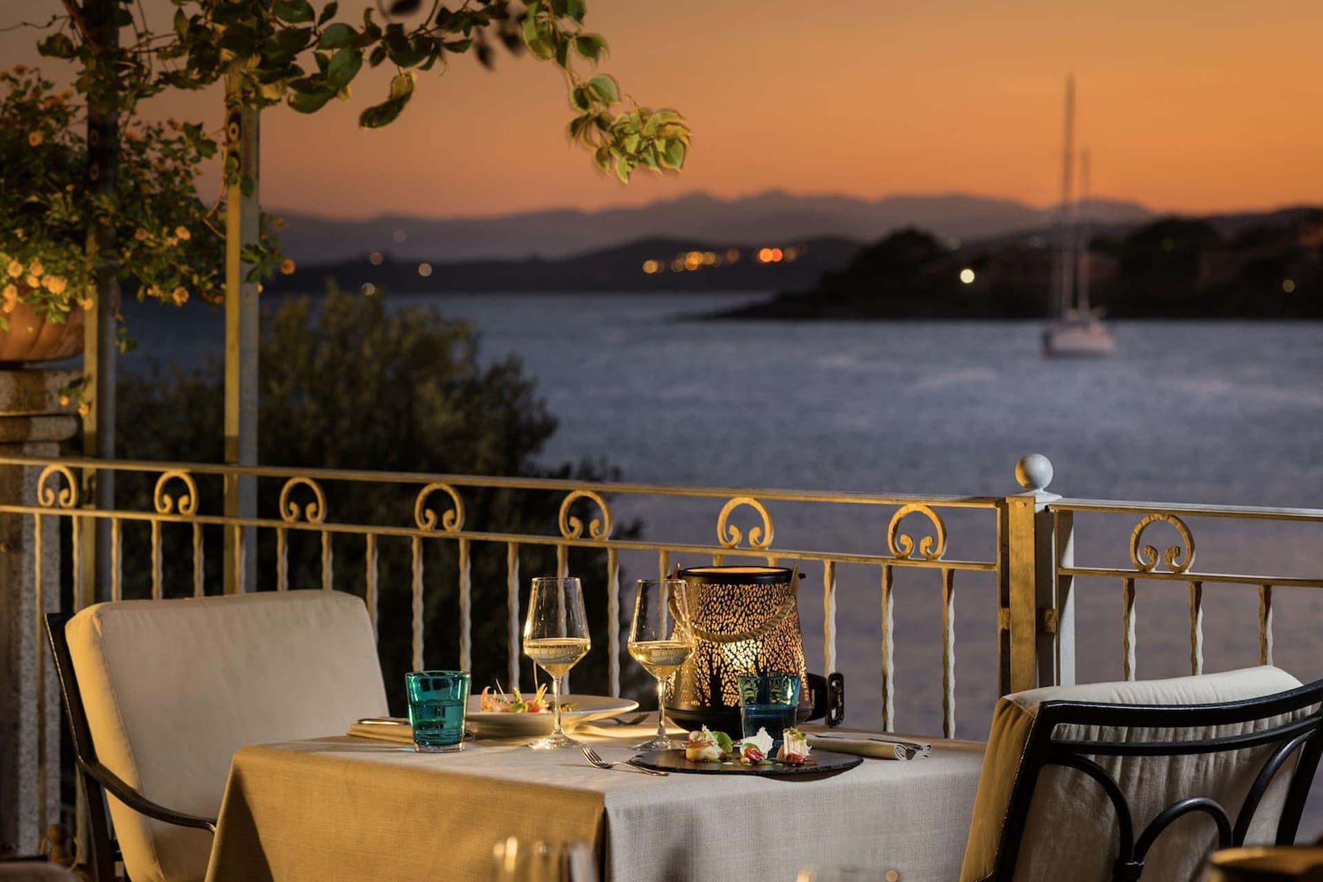 A table set for dining with a view of the water and mountains in the background.