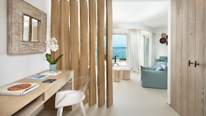 Una sala de estar moderna con un separador de madera, un comedor con mesa y sillas, y vista al mar.