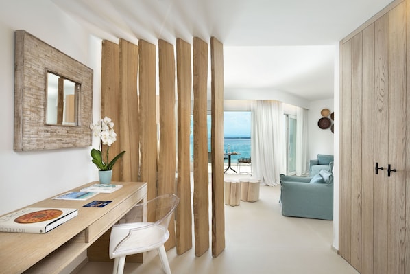 Een moderne woonkamer met een houten roomdivider, een eethoek met een tafel en stoelen, en uitzicht op zee.