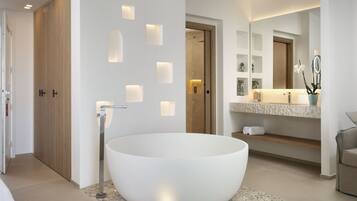 A modern bathroom with a large freestanding bathtub, recessed wall lighting, and a vanity with a mirror and shelves.