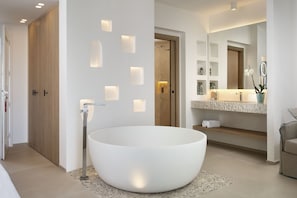 Une salle de bain moderne dotée d’une grande baignoire sur pied, d’un éclairage encastré dans les murs et d’un meuble-lavabo avec un miroir et des étagères.