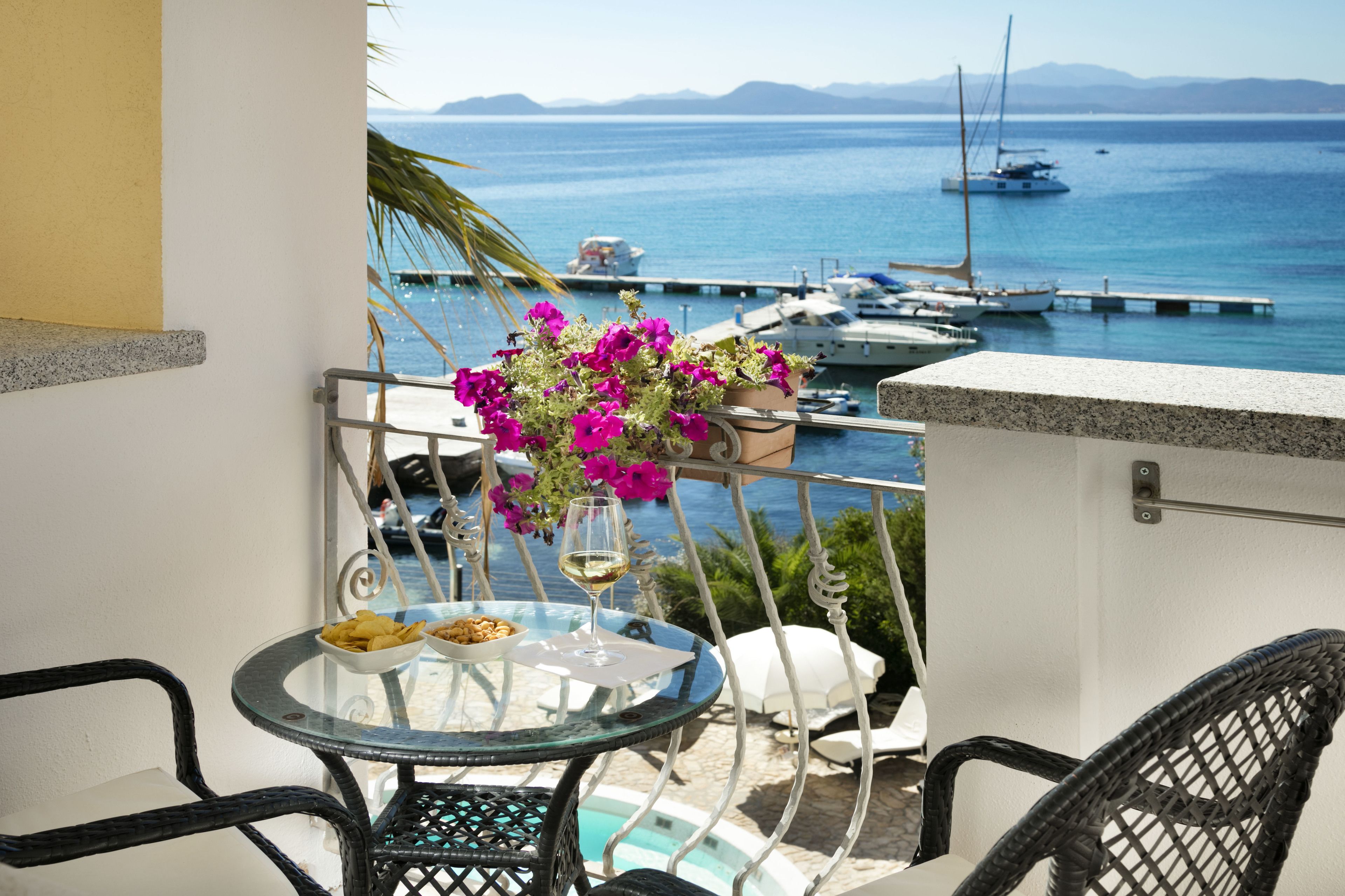 Un balcon avec une table en verre, des chaises et un arrangement floral.