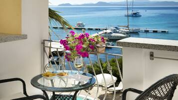 Un balcon avec une table en verre, des chaises et un arrangement floral.