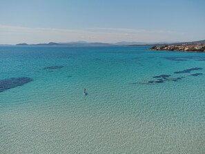 Un paysage côtier avec une eau turquoise cristalline et des montagnes à l’horizon.