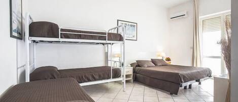 A room with bunk beds, a bedside table with a lamp, and a window with curtains.
