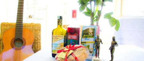 A table with a guitar, a bottle of wine, a wrapped gift, a book, and a plant.