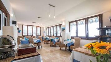 A dining area with tables set for service, a buffet station, and a large window providing natural light.