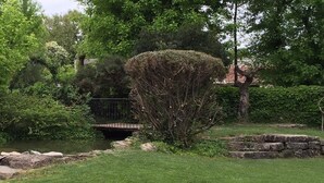 A garden with a pond, a stone bridge, and a variety of trees and shrubs. - Il Leone D'Oro (Telgate)