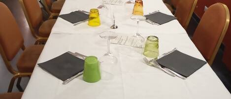 A long dining table with chairs, set with wine glasses, napkins, and a menu.