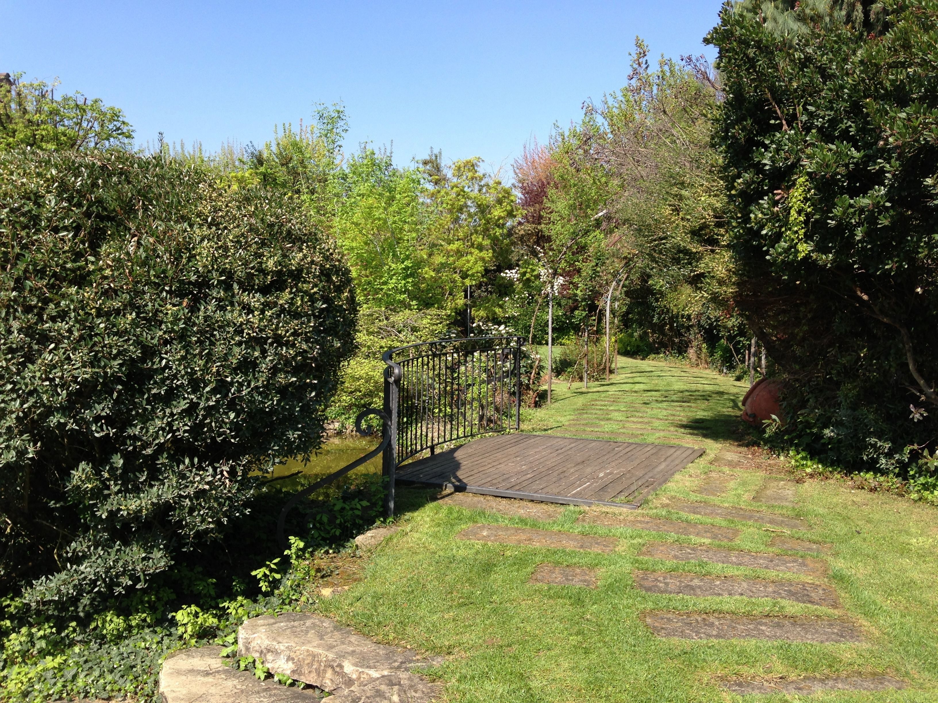 A pathway leading through a garden with a wooden deck and metal railing.