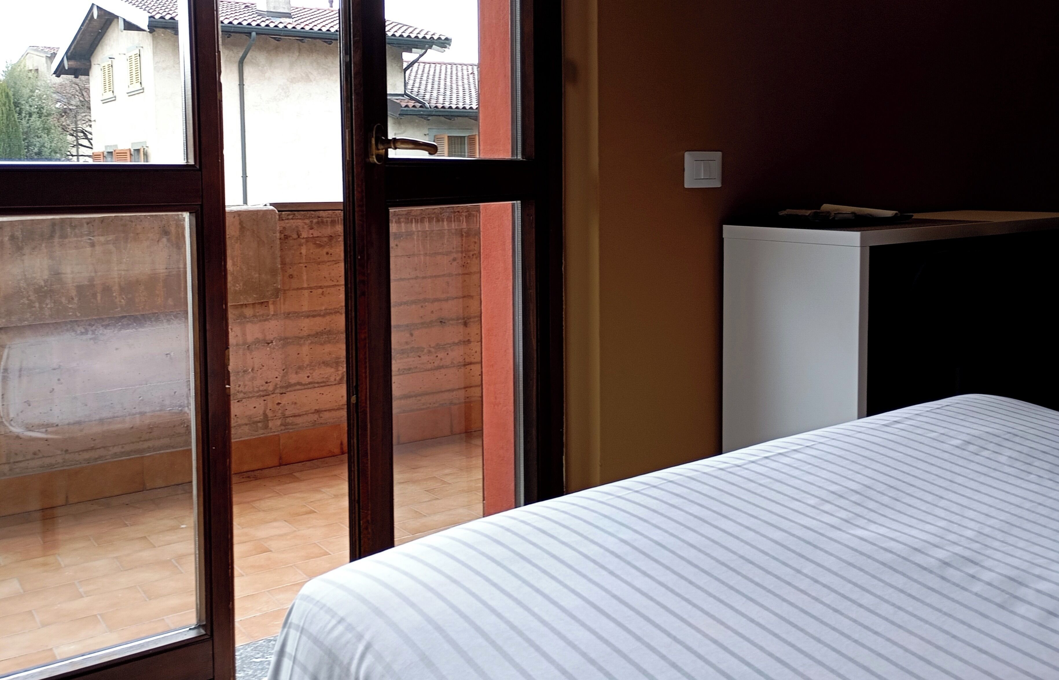 A room with a bed, a window, and a view of a building outside.