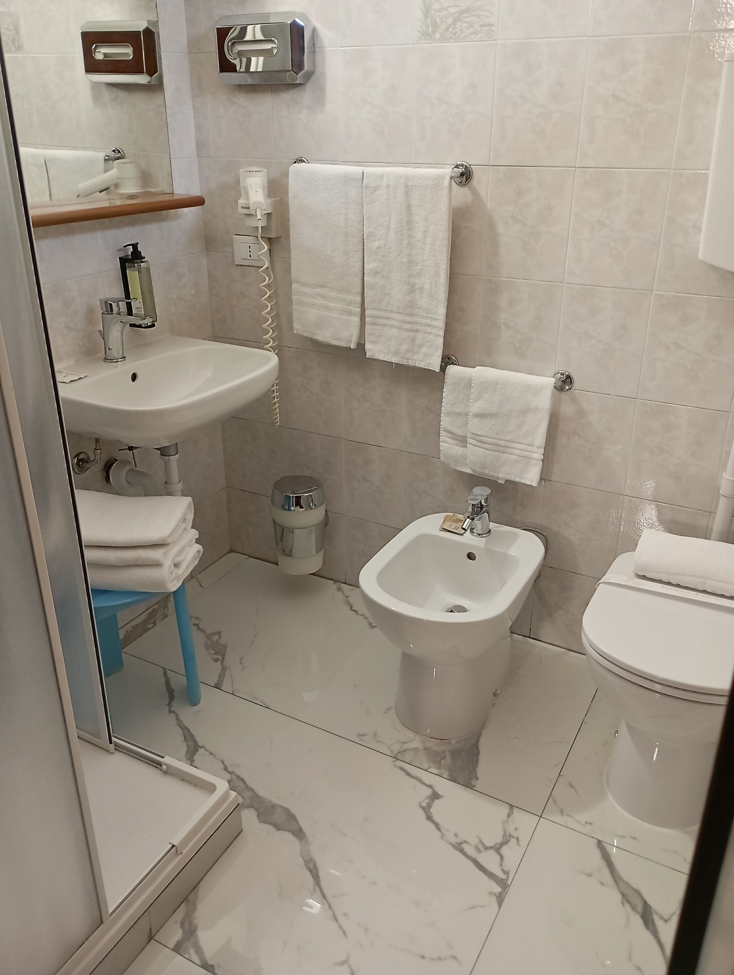 A bathroom with a sink, bidet, toilet, and towels.