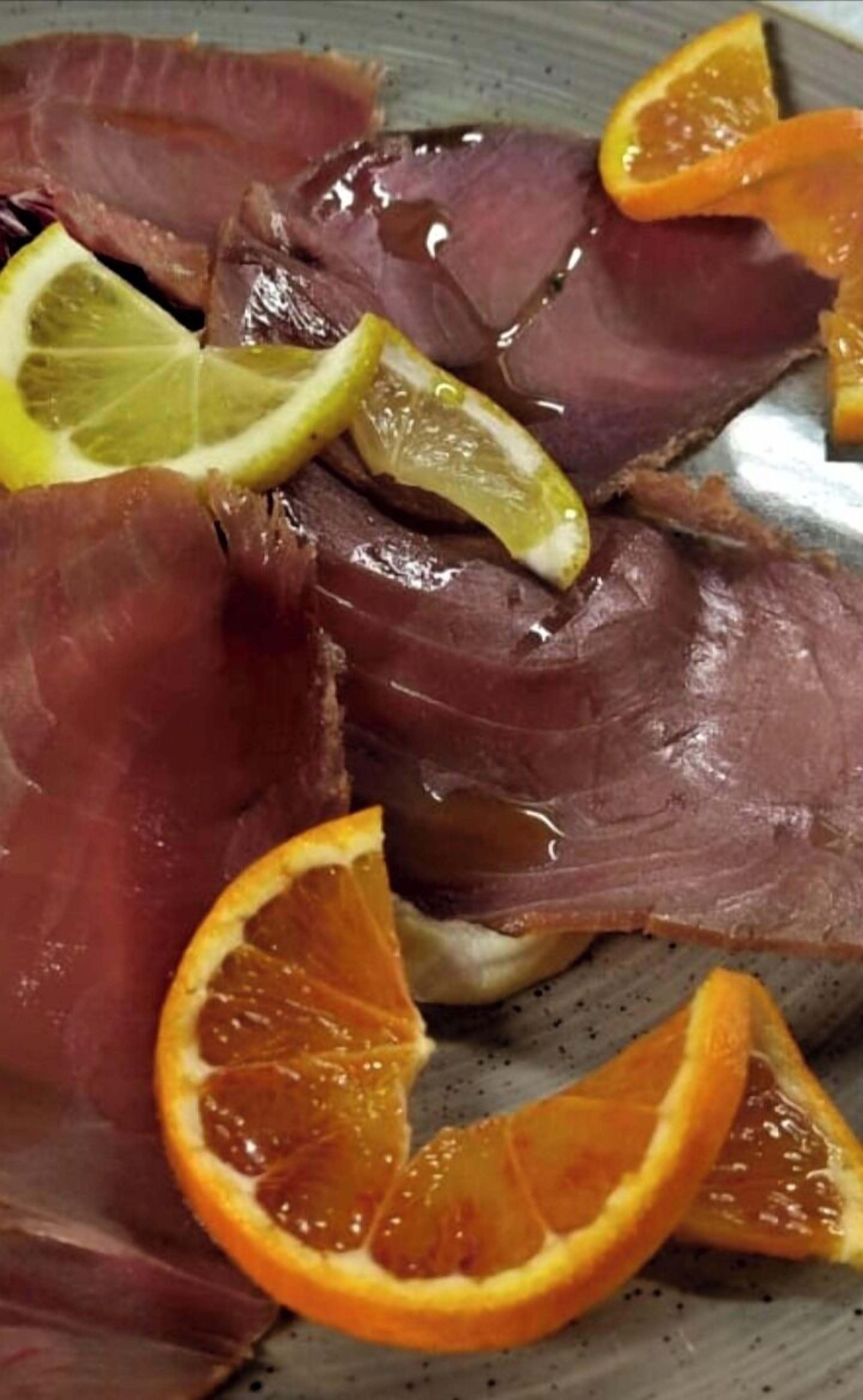 Un plato con lonchas de carne y rodajas de naranja.