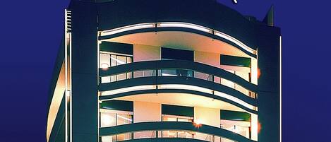 A multi-story hotel with a curved facade, illuminated windows, and a sign reading 'Park Hotel' at the top.