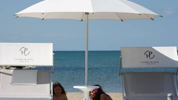 Two white lounge chairs with 'Park Hotel' branding, a white umbrella, and a small table with a white cloth.