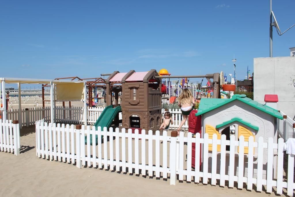 Un parque infantil con un tobogán, estructuras para escalar y una zona de juegos vallada.
