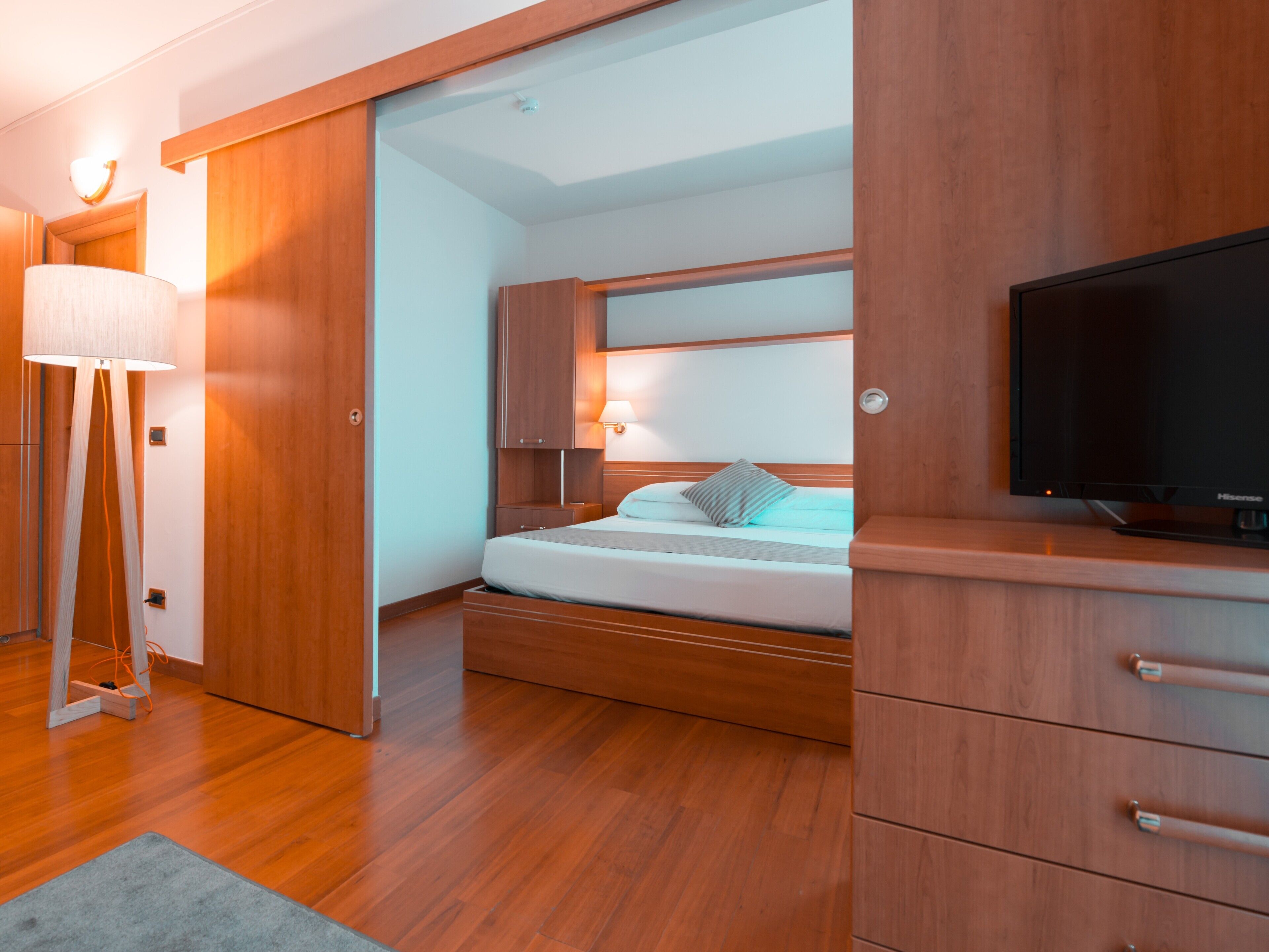 A modern bedroom with a bed, wooden wardrobe, and a television.