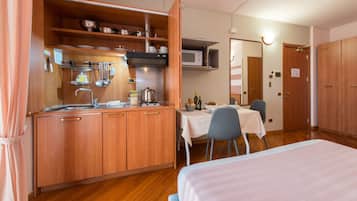 Una cocina compacta con armarios de madera, un microondas y un comedor con mesa y sillas.