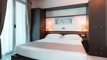A hotel room with a large bed, a painting on the wall, and a wardrobe.