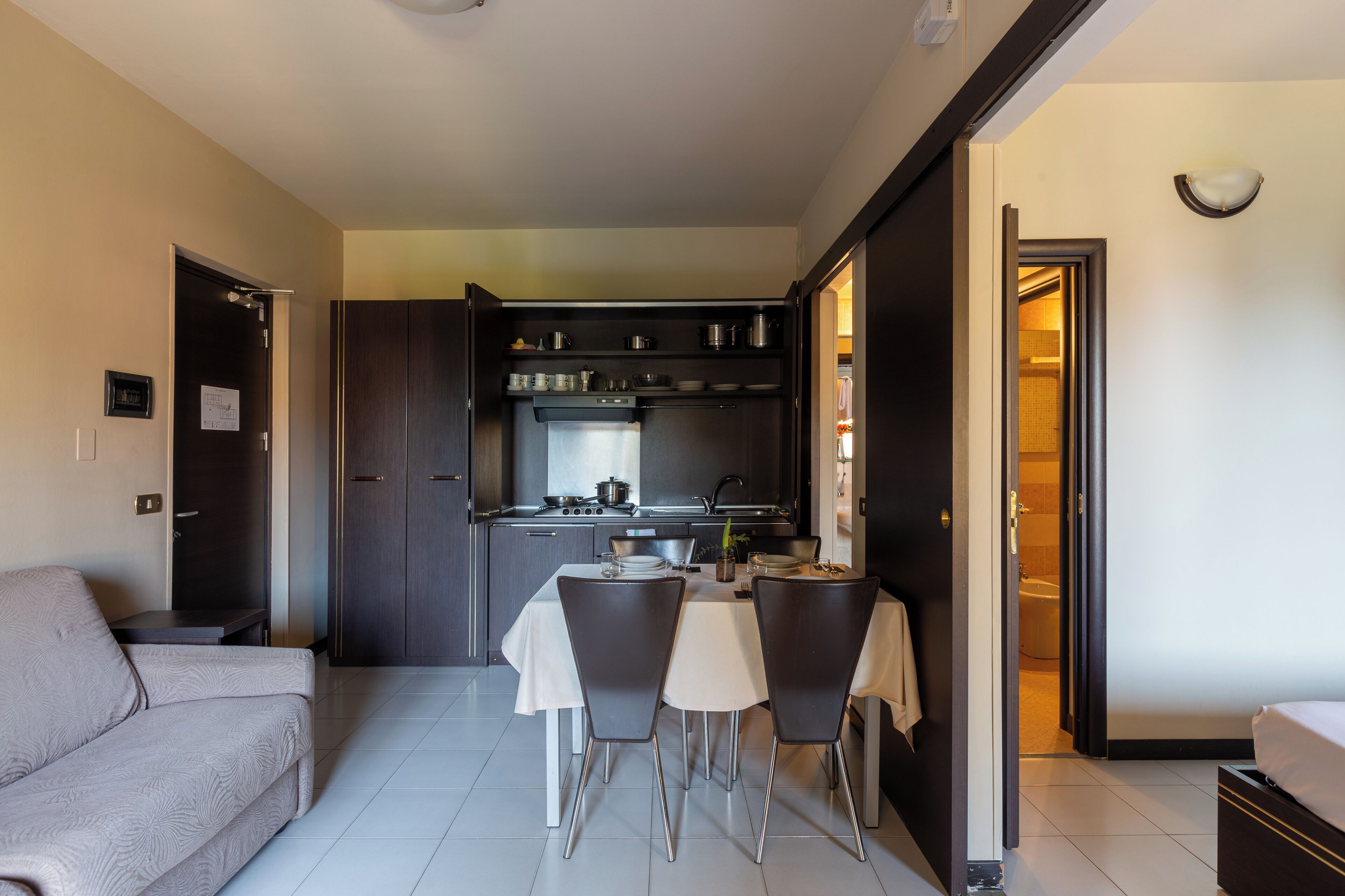 Un espacio habitable compacto con kitchenette, una zona de comedor con mesa y sillas, y un sofá.