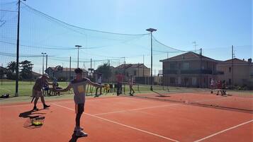 A tennis court with a net, players, and tennis balls.